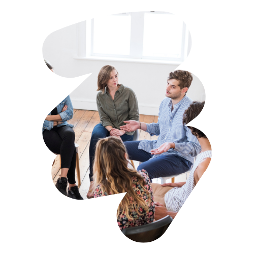 In a brightly lit room, a group of people sit in a circle engaged in discussion about mental health treatment. They appear attentive and focused, embodying the compassionate spirit of Chicago. The image is creatively cropped in an abstract shape.